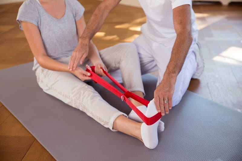 Терапевт показва упражнение с колан